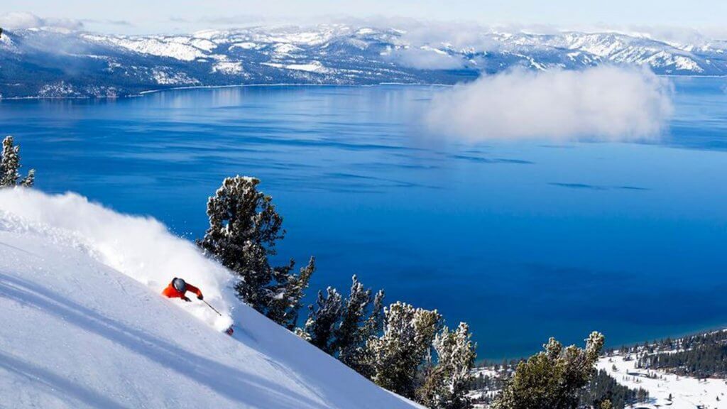 Skiing in deep powder snow on bluebird day at Heavenly Mountain Resort at Lake Tahoe